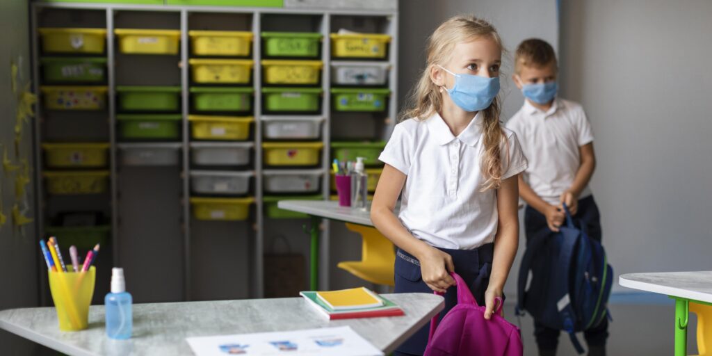 Children in clean, organised Manchester school classroom with sanitised desks and storage areas