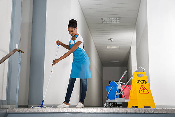 Cleaning company Manchester employee using a mop and bucket to clean a bright living room floor.