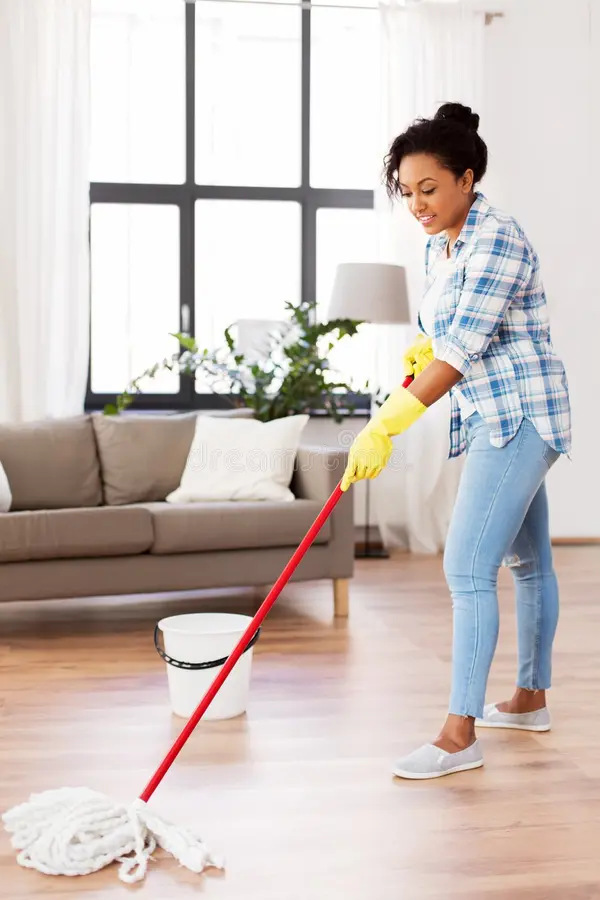 Professional cleaning services Manchester woman mopping a bright modern home hardwood floor.